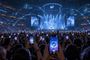 Público en un estadio multitudinario con teléfonos móviles iluminados y gráficos superpuestos de conectividad 5G SA y Movistar Arena.