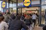 Multitud de clientes con carritos de la compra esperando en la entrada de un supermercado Lidl, identificador 25T134422.