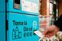Primer plano de una máquina de reciclaje azul Volta donde una persona recoge un ticket tras depositar envases.