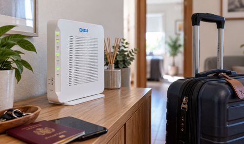 Router de fibra de la operadora DIGI en el aparador de una vivienda junto a una maleta de viaje.