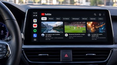 Interfaz de YouTube abierta en la pantalla central del salpicadero de un coche a través de Android Auto.