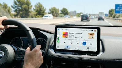 Interfaz de Android Auto en la pantalla de un coche mostrando la aplicación de radio durante la conducción por autopista.