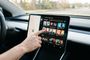 Una persona toca la pantalla central de un coche que muestra la interfaz de YouTube en Android Auto.