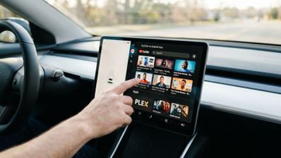 Una persona toca la pantalla central de un coche que muestra la interfaz de YouTube en Android Auto.
