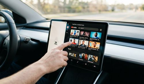 Una persona toca la pantalla central de un coche que muestra la interfaz de YouTube en Android Auto.