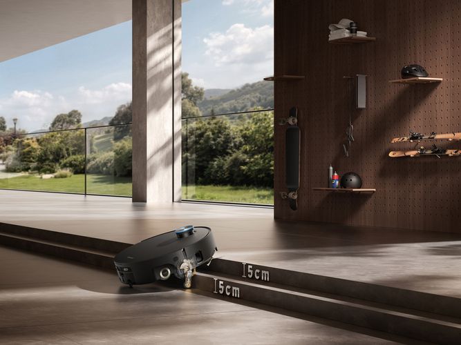 Robot aspirador superando un escalón de cinco centímetros en una vivienda con vistas al exterior.