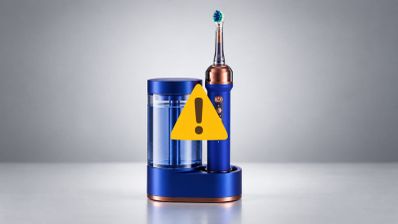 Cepillo de dientes eléctrico Dyson en color azul y cobre sobre su base de carga con depósito de agua.