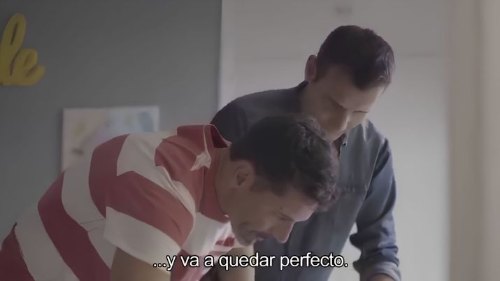 Dos hombres adultos observan con atención una tarea o superficie frente a ellos en un entorno doméstico.