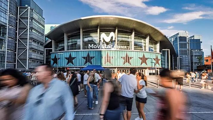 Fachada principal del Movistar Arena con gente caminando por la plaza exterior durante el día.