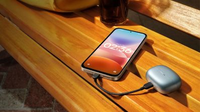 Teléfono inteligente conectado mediante cable USB-C a un estuche de auriculares inalámbricos sobre un banco de madera.