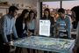 Grupo de profesionales analizando un mapa urbano interactivo y un documento del BOE proyectado en una mesa digital.