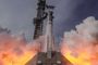 Lanzamiento de un cohete espacial de gran tamaño rodeado de nubes de humo y fuego en la base.