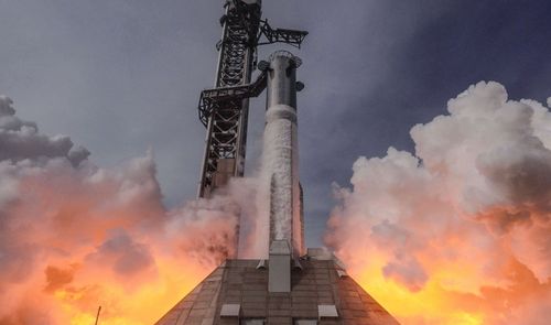 Lanzamiento de un cohete espacial de gran tamaño rodeado de nubes de humo y fuego en la base.
