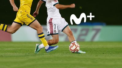 Dos futbolistas disputando un balón en un partido de Primera Federación con el logotipo de Movistar Plus+ sobreimpreso.