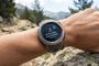 Reloj inteligente Garmin Instinct en una muñeca mostrando una barra de progreso de actualización de software en un entorno de montaña.