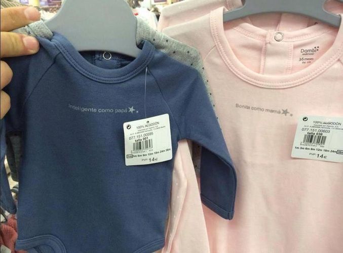 Dos bodies infantiles colgados, uno azul con el texto 'inteligente como papá' y otro rosa con 'bonita como mamá'.