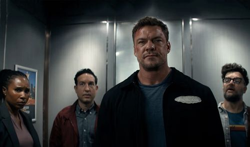 Alan Ritchson como Jack Reacher junto a otros tres personajes en el interior de un ascensor metálico.