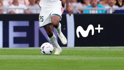 Primer plano de las piernas de un futbolista con el balón y el logotipo de Movistar Plus+ al fondo.