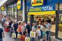 Fila de personas esperando para entrar en un supermercado Lidl bajo un cartel de ahorro total.