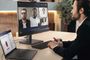 Usuario en una oficina realizando una videollamada grupal con un portátil Lenovo conectado a un monitor externo.
