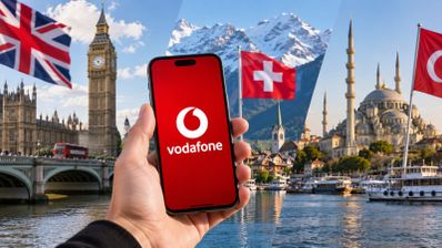 Mano sosteniendo un teléfono móvil con el logotipo de Vodafone frente a paisajes de Londres, Suiza y Turquía.