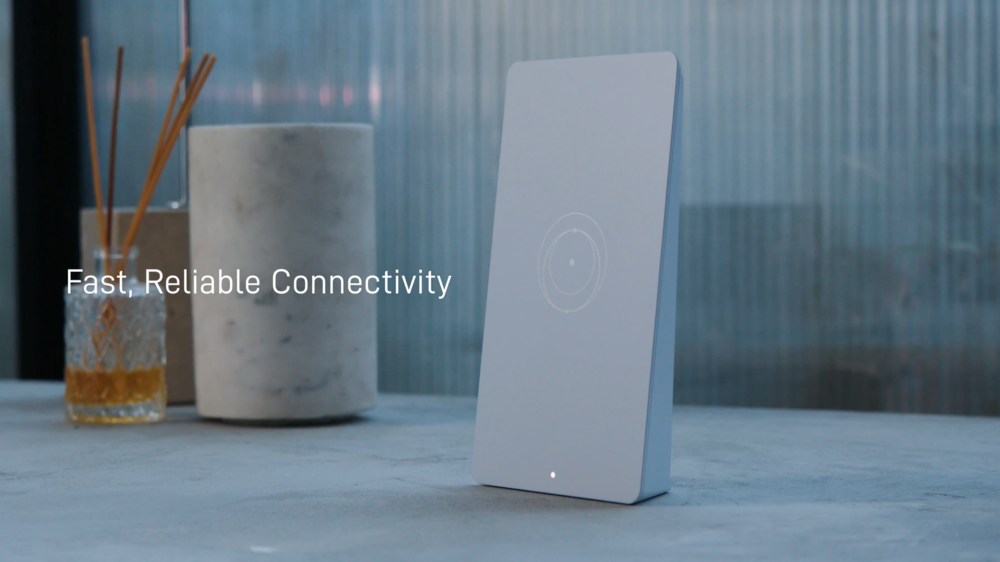 Router con tecnología WiFi 7 de diseño minimalista y vertical sobre una mesa junto a elementos decorativos.