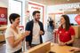 Empleada de Vodafone atendiendo a varios clientes en el mostrador de una tienda física.