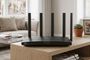 Router TP-Link de color negro con seis antenas externas sobre un mueble de madera en un salón.