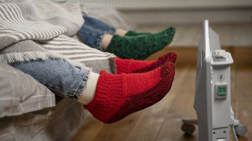 Pies de dos personas calentándose con la calefacción