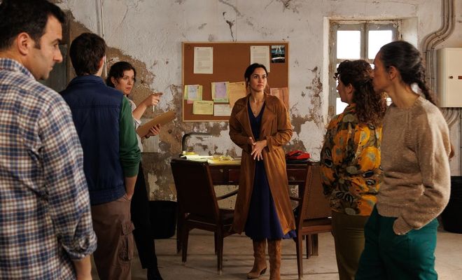 Grupo de personajes reunidos en una estancia rústica con paredes desconchadas y un tablón de anuncios en la serie Entre tierras.