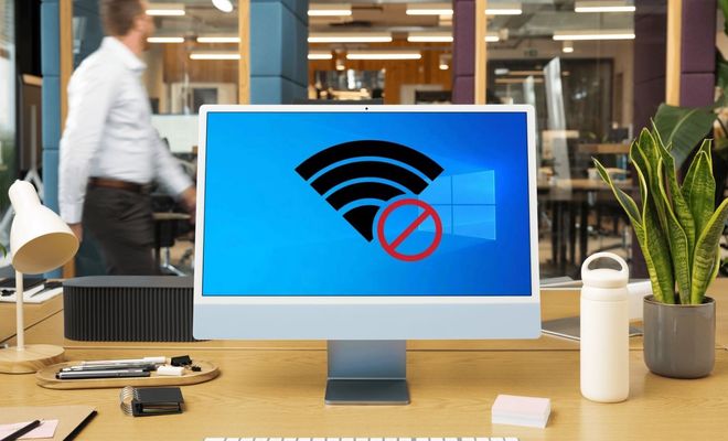 Icono de señal WiFi con símbolo de prohibido sobre el logotipo de Windows en la pantalla de un ordenador de escritorio en una oficina.