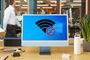 Icono de señal WiFi con símbolo de prohibido sobre el logotipo de Windows en la pantalla de un ordenador de escritorio en una oficina.