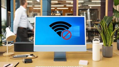 Icono de señal WiFi con símbolo de prohibido sobre el logotipo de Windows en la pantalla de un ordenador de escritorio en una oficina.