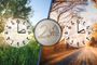 Composición de dos relojes marcando el cambio de hora entre verano e invierno junto a una moneda de dos euros.