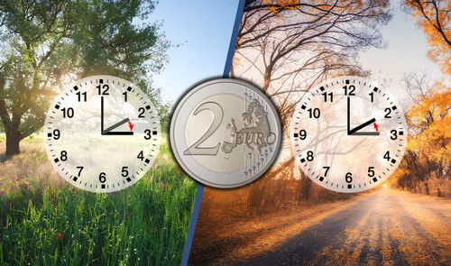Composición de dos relojes marcando el cambio de hora entre verano e invierno junto a una moneda de dos euros.