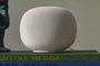 Altavoz inteligente Google Nest Mini de color blanco sobre una pila de libros.