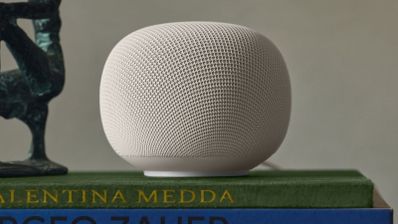 Altavoz inteligente Google Nest Mini de color blanco sobre una pila de libros.