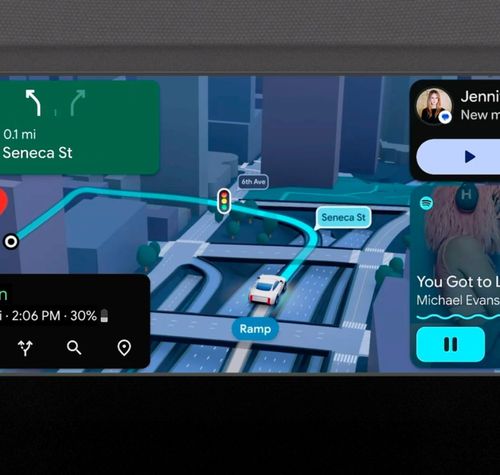 Interfaz de Android Auto 18.1 con navegación por mapa en 3D, controles de reproducción de Spotify y notificación de mensaje entrante en pantalla panorámica.