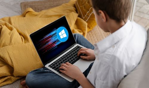 Persona utilizando un ordenador portátil que muestra el logotipo de Windows sobre un fondo de líneas de velocidad.