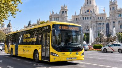 Autobús amarillo de la línea Exprés Aeropuerto circulando por la Plaza de Cibeles en Madrid.