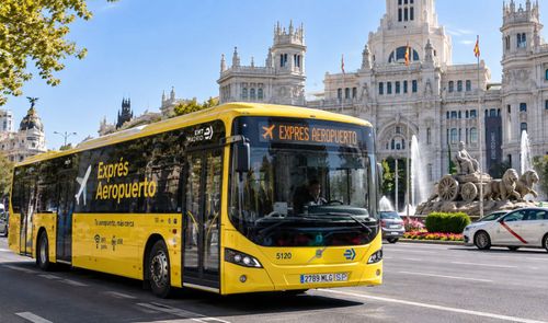Autobús amarillo de la línea Exprés Aeropuerto circulando por la Plaza de Cibeles en Madrid.