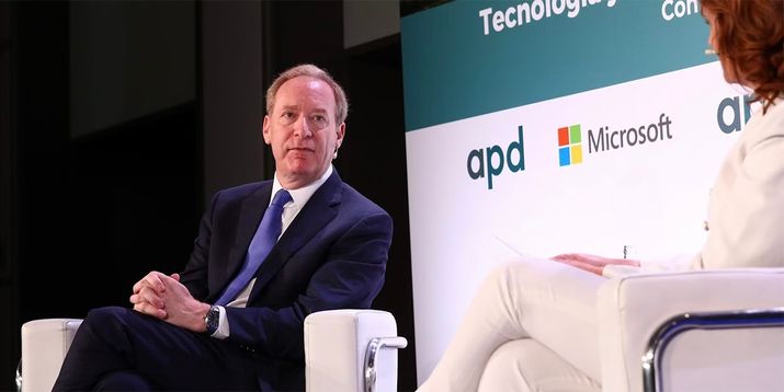 Brad Smith sentado en un escenario durante un evento corporativo de Microsoft.