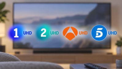 Logotipos de La 1, La 2, Antena 3 y Telecinco con el indicativo UHD sobre un televisor en un salón.