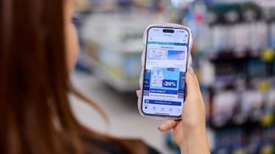 Persona consultando promociones y cupones de descuento en la aplicación de Carrefour desde un teléfono móvil en el interior de un supermercado.