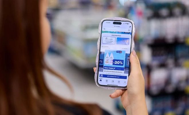 Persona consultando promociones y cupones de descuento en la aplicación de Carrefour desde un teléfono móvil en el interior de un supermercado.
