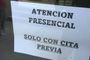 Cartel informativo en una puerta de cristal con el texto Atención Presencial solo con cita previa.