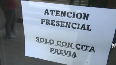 Cartel informativo en una puerta de cristal con el texto Atención Presencial solo con cita previa.