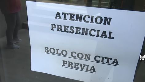 Cartel informativo en una puerta de cristal con el texto Atención Presencial solo con cita previa.
