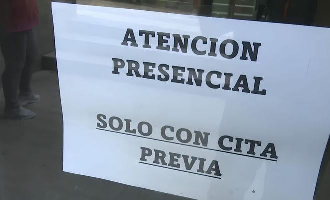 Cartel informativo en una puerta de cristal con el texto Atención Presencial solo con cita previa.