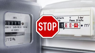 Primer plano de un contador de luz y un contador de gas analógico con una señal de stop superpuesta.
